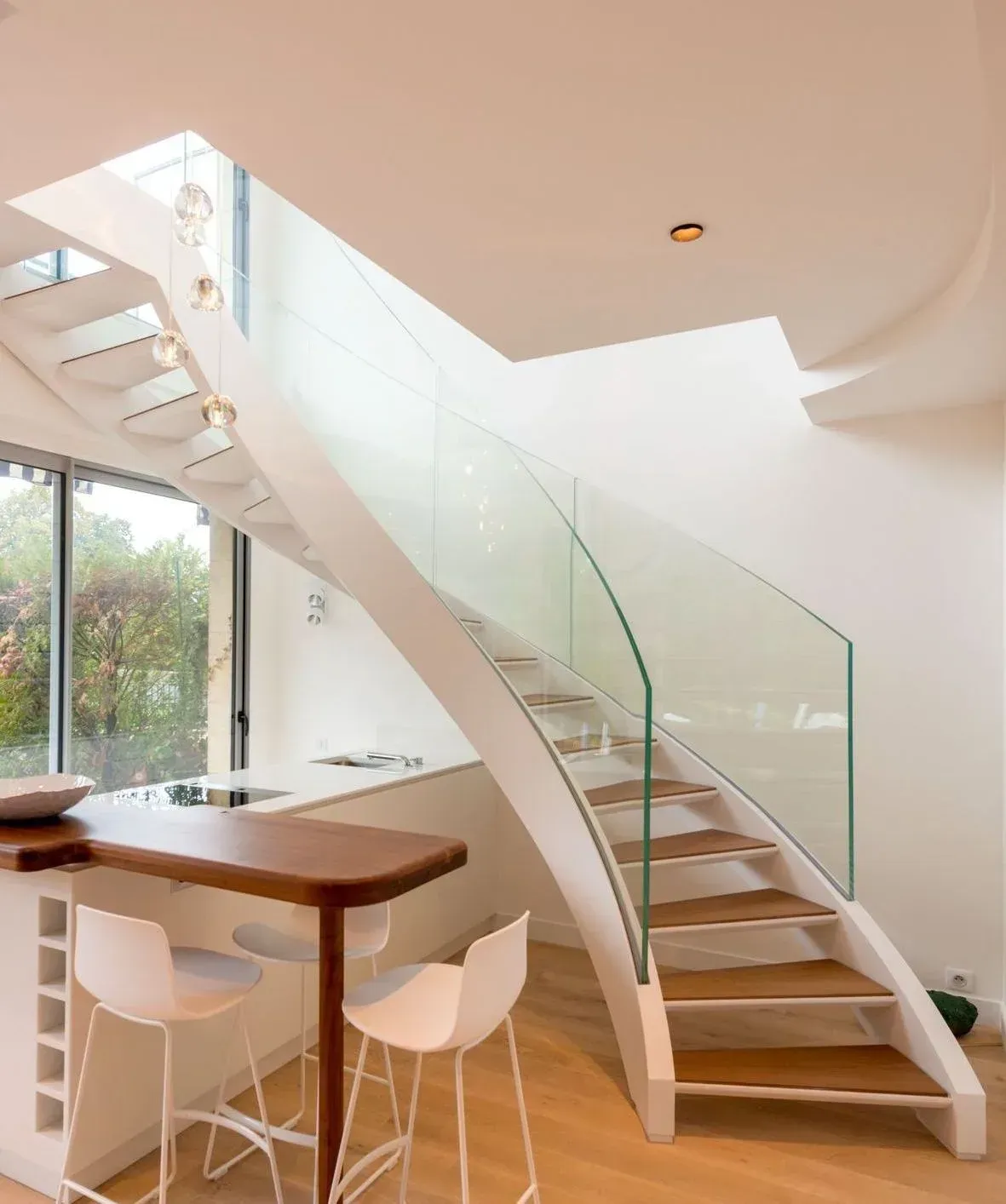 Una cocina con una escalera curva y una barandilla de cristal.
