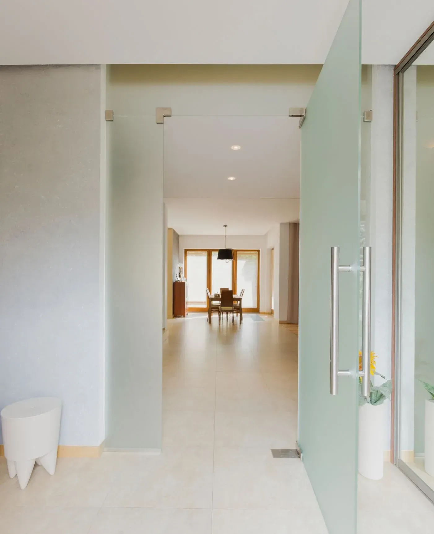 Una puerta de vidrio se abre a un comedor con una mesa y sillas.