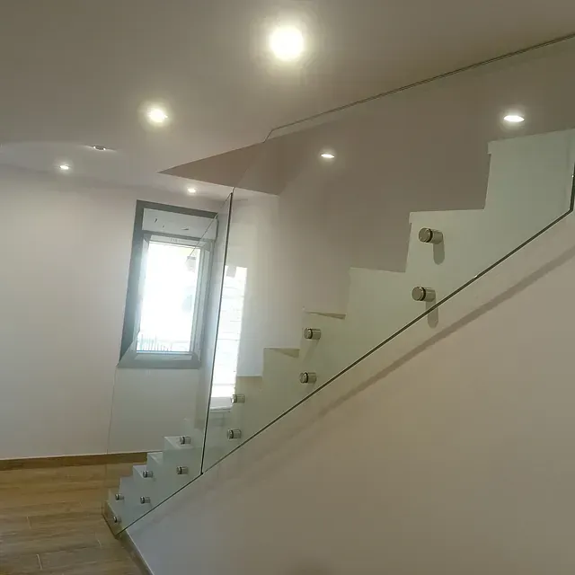 Una escalera con barandilla de cristal en una habitación con ventana.