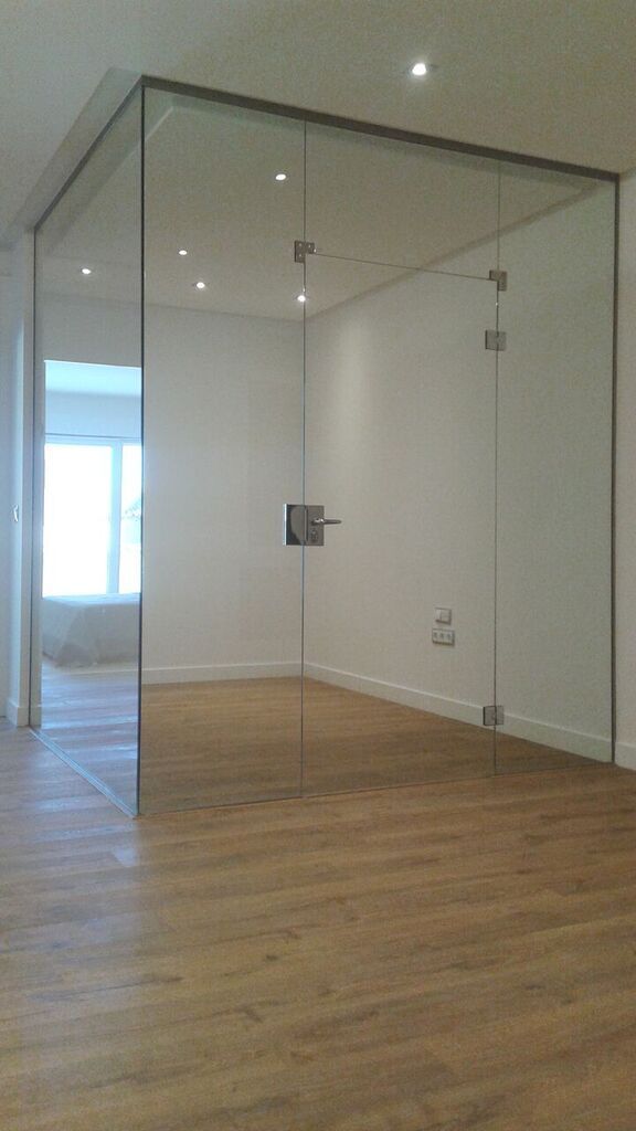 Una habitación vacía con una pared de cristal y suelo de madera.