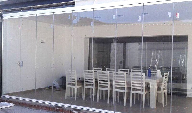 Un comedor con una mesa y sillas detrás de una pared de cristal.