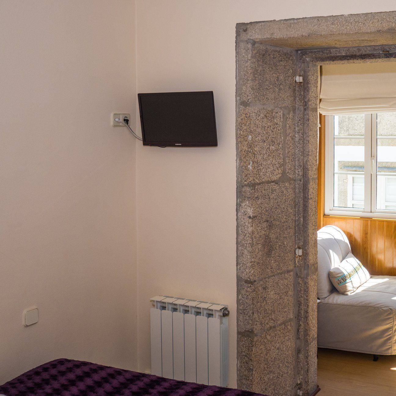 Un dormitorio con una cama y un televisor en la pared.