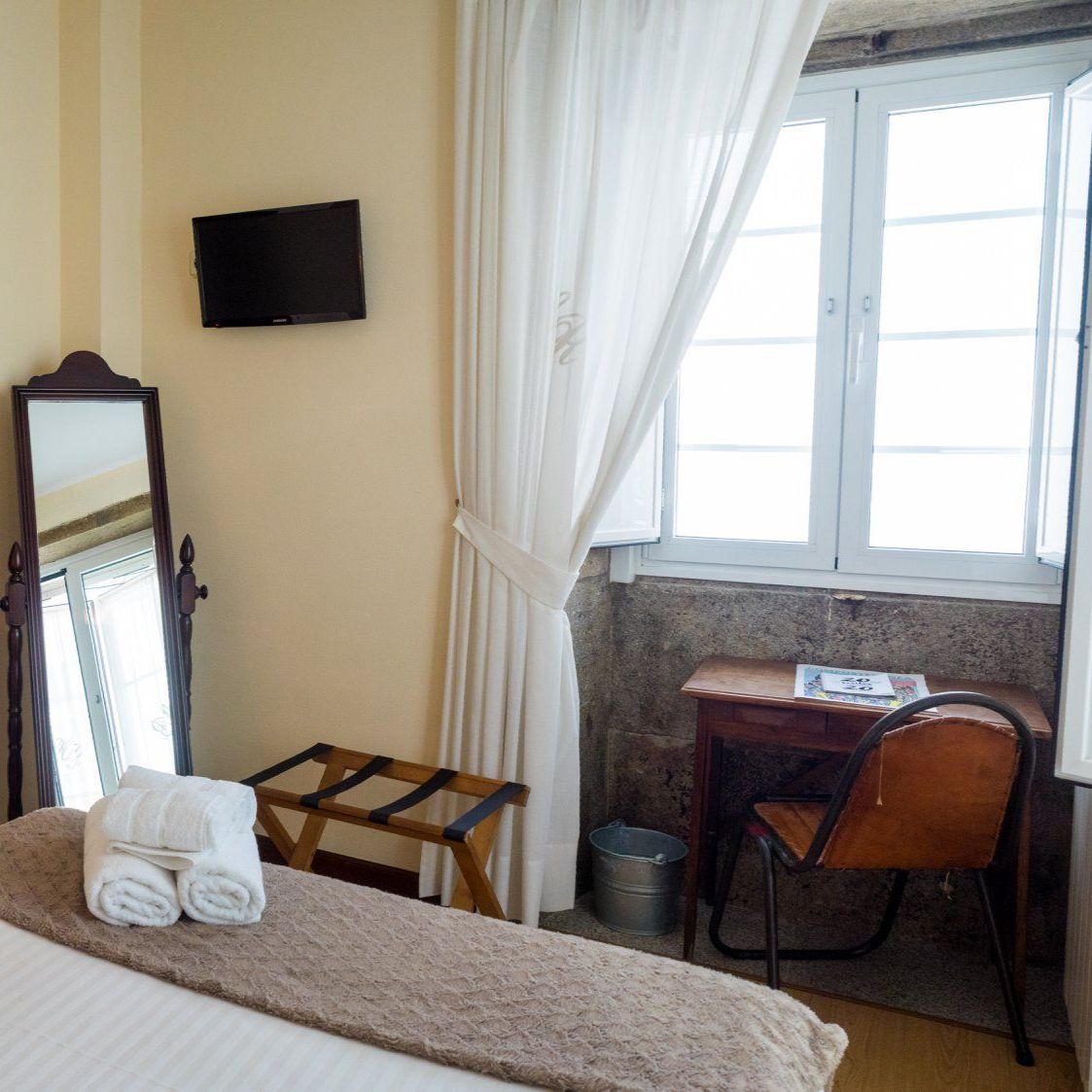 Un dormitorio con una cama, un escritorio y un espejo.