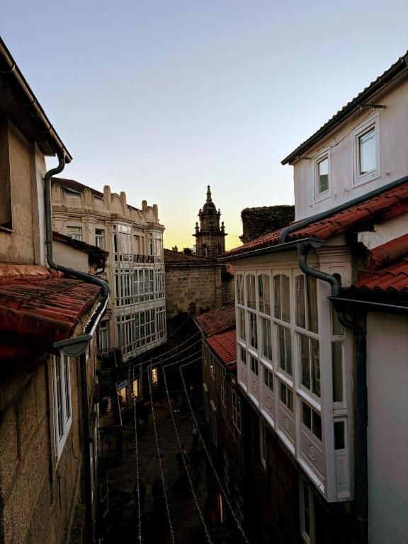 Un callejón estrecho entre dos edificios con una torre de reloj al fondo.