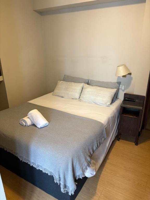Un dormitorio con cama, mesita de noche y lámpara.