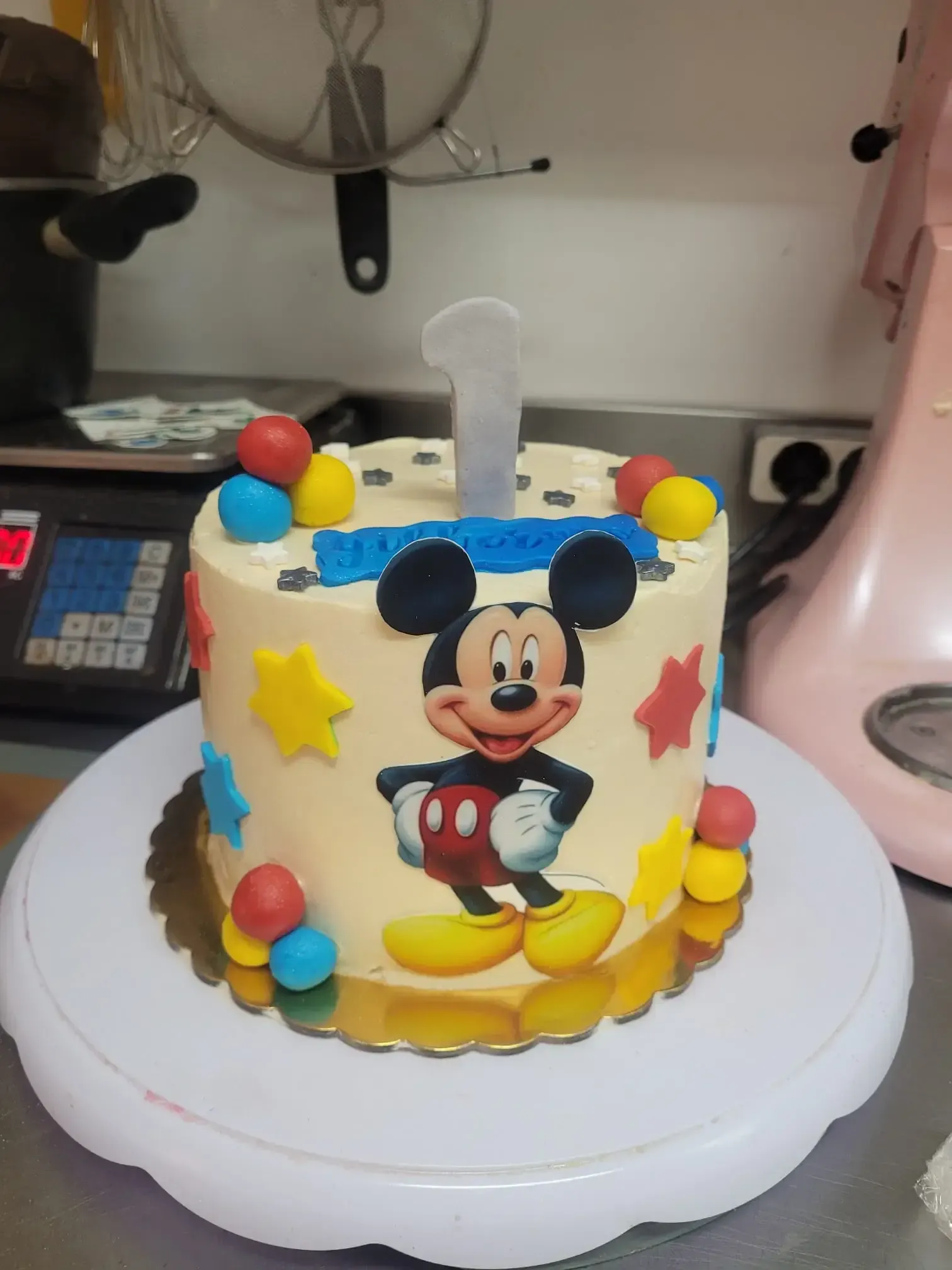 Tarta de cumpleaños de Mickey Mouse con bolas de fondant de colores sobre un soporte blanco