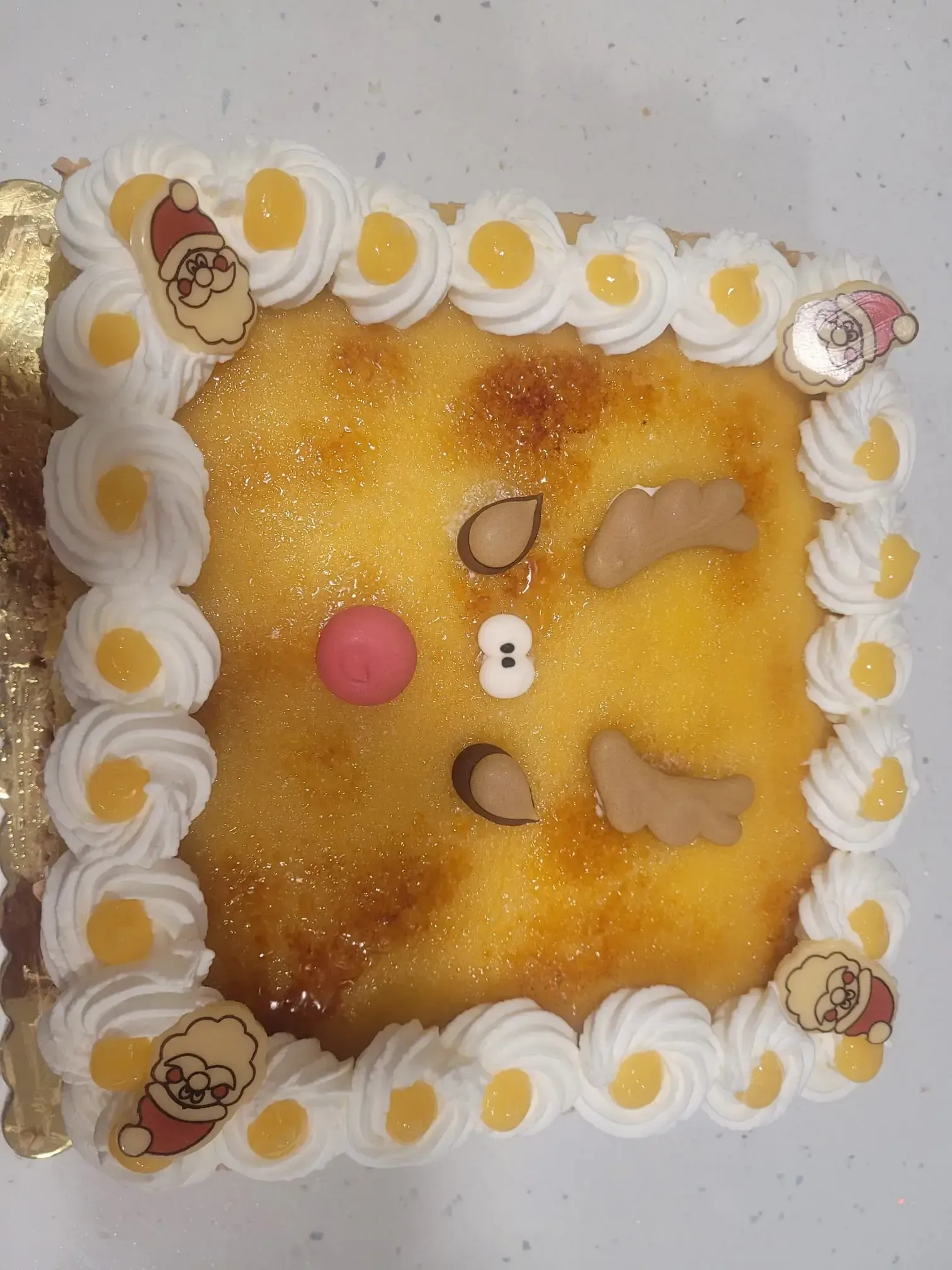 Pastel cuadrado con glaseado amarillo, borde blanco hecho con manga pastelera y adornos de caritas de animales adorables