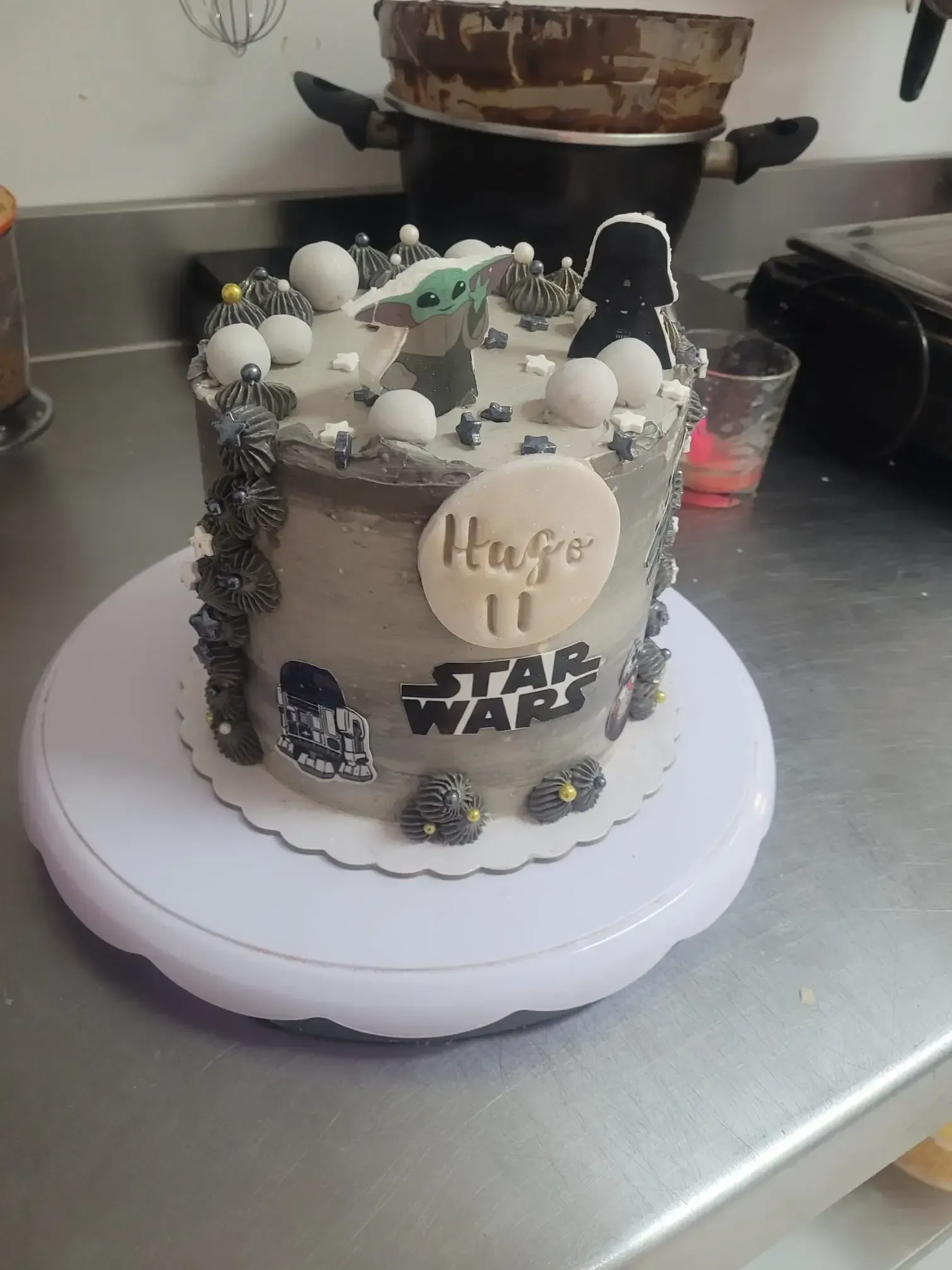 Pastel temático de Star Wars con glaseado blanco y cobertura de chocolate, sobre una encimera de cocina
