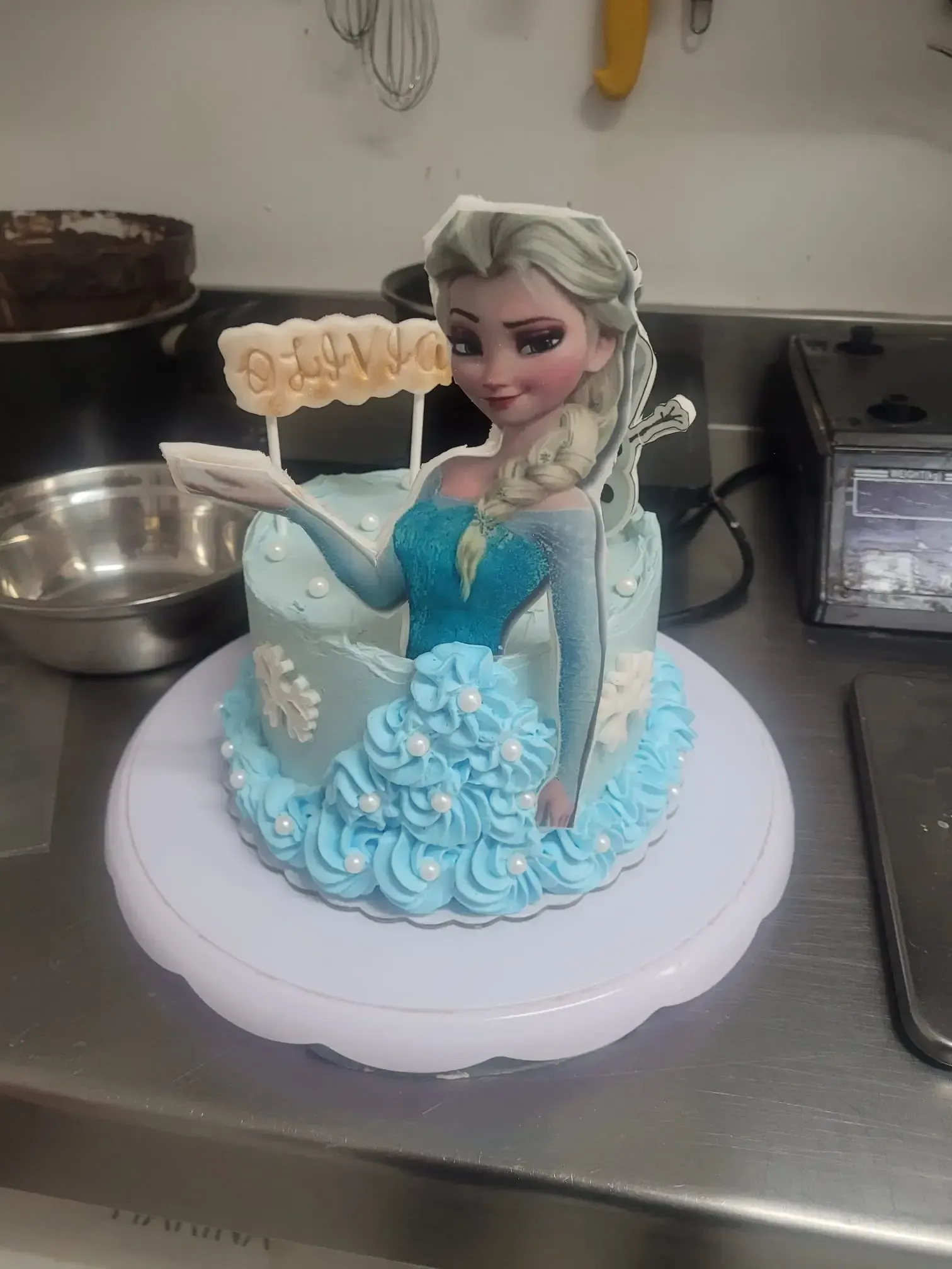 Adorno para tarta de Elsa de Frozen azul sobre una base blanca, en una cocina