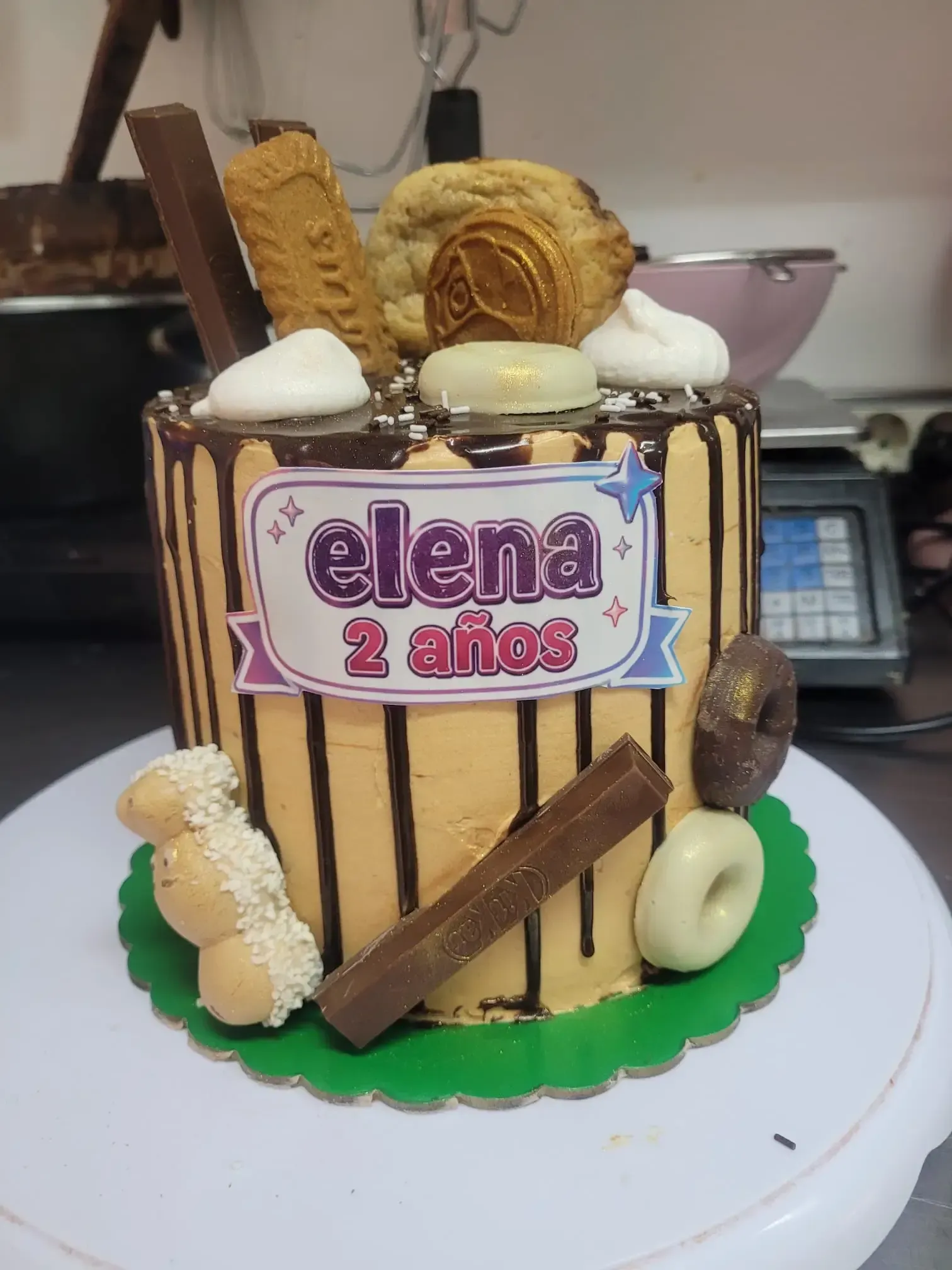 Tarta de cumpleaños con topper de «Elena 2 anos», chorreaduras de chocolate, barquillos, galletas y detalles de crema blanca