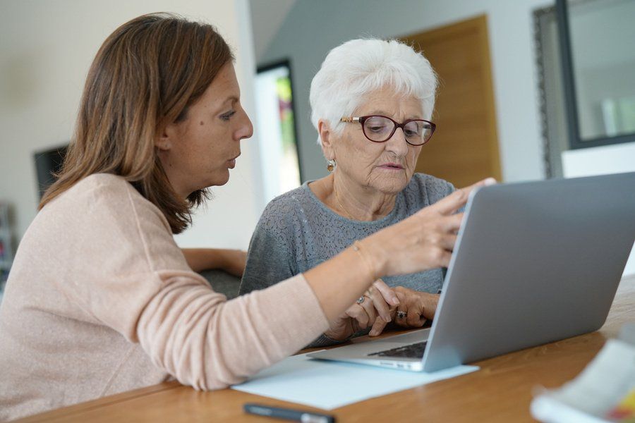 Femme aidant une personne âgée à utiliser son ordinateur