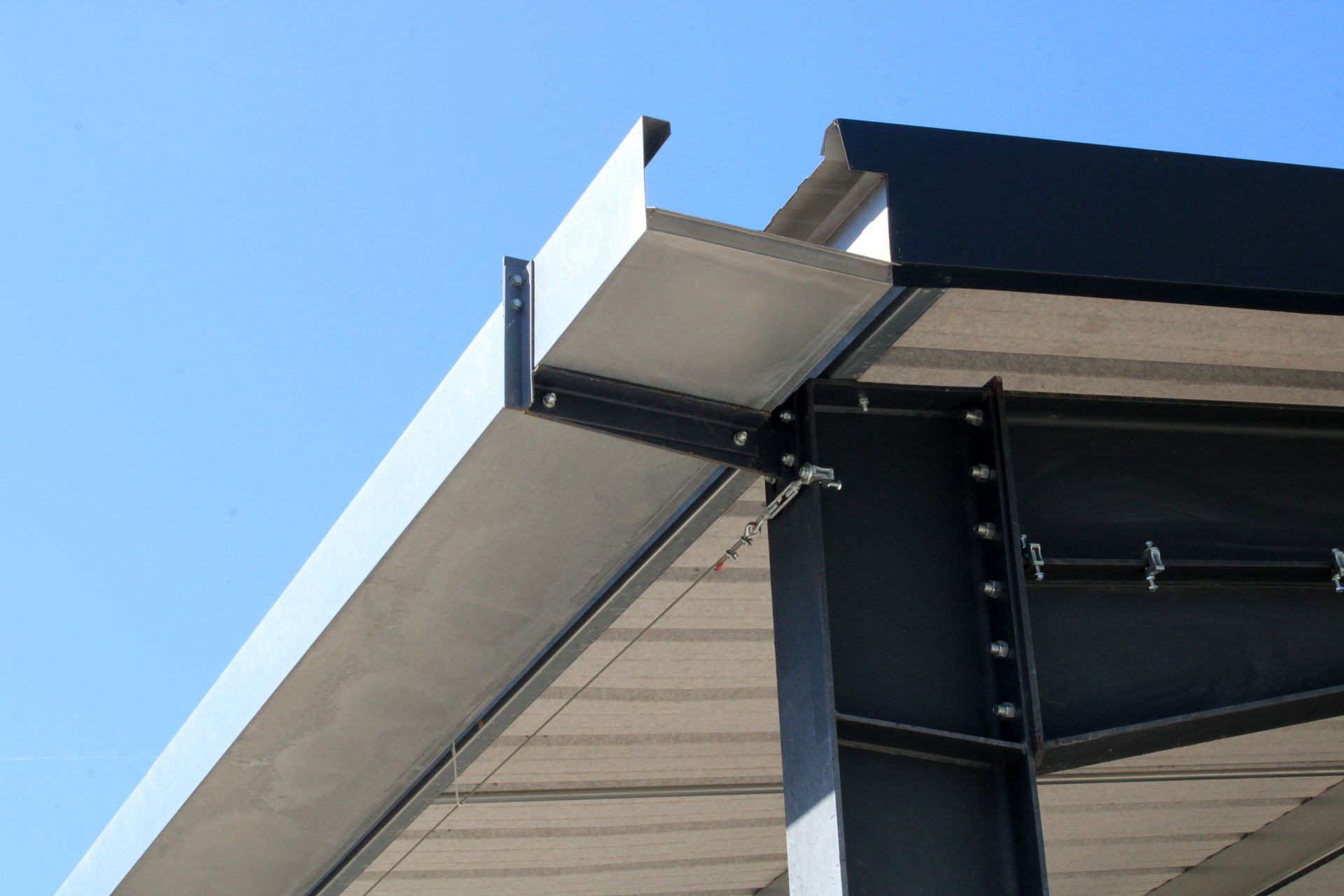 Gros plan sur le bord du toit d'un bâtiment moderne avec une garniture métallique sur fond de ciel bleu