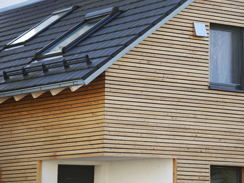 Extérieur de maison moderne avec toit gris foncé et bardage en bois clair