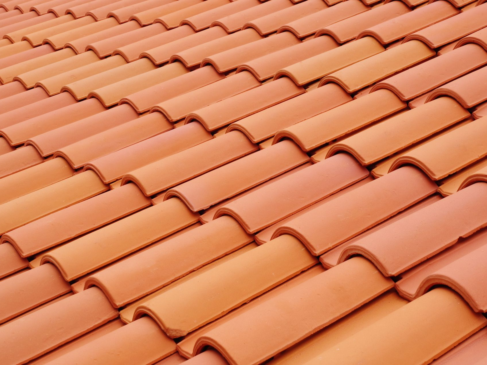 Des rangées de tuiles en terre cuite orange sur un toit en pente