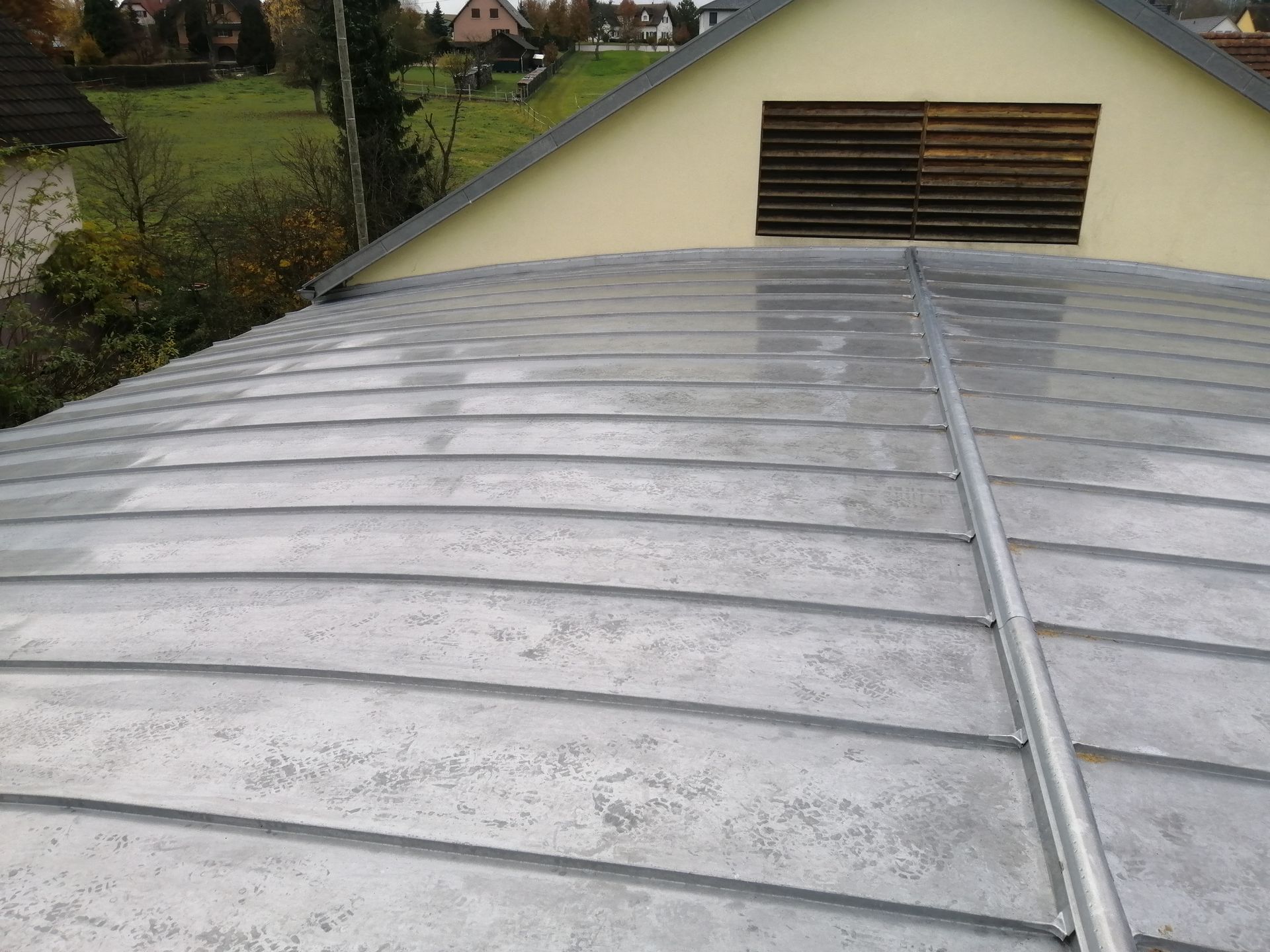 Toiture métallique incurvée avec pignon ventilé, vue de dessus dans une zone résidentielle