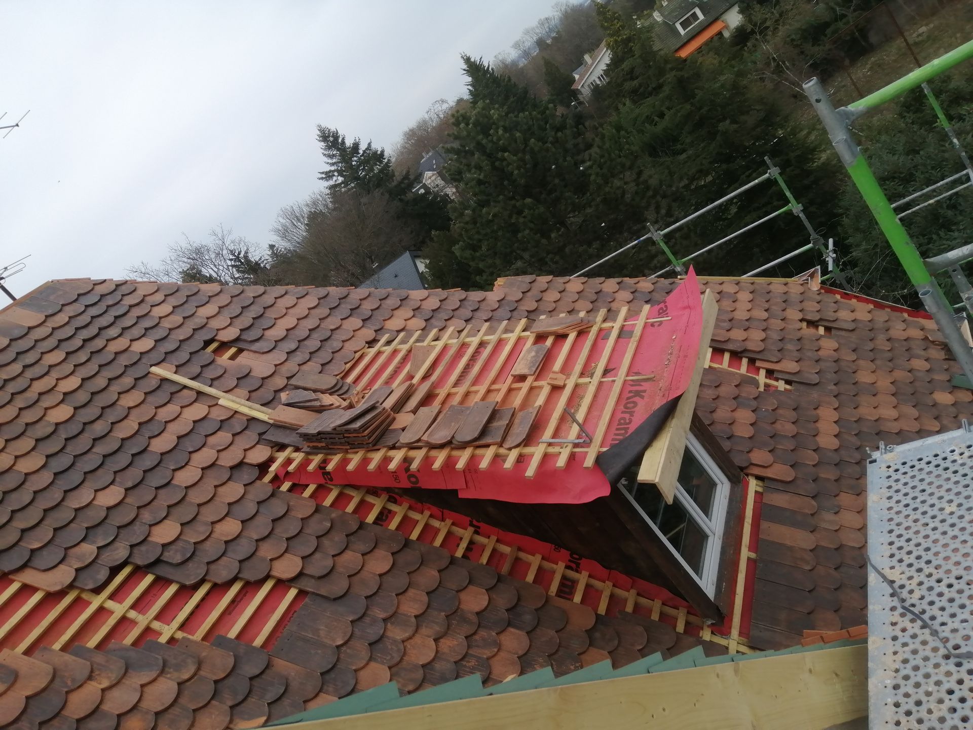 Toiture en tuiles en cours, avec une fenêtre de combles apparente, vue du dessus