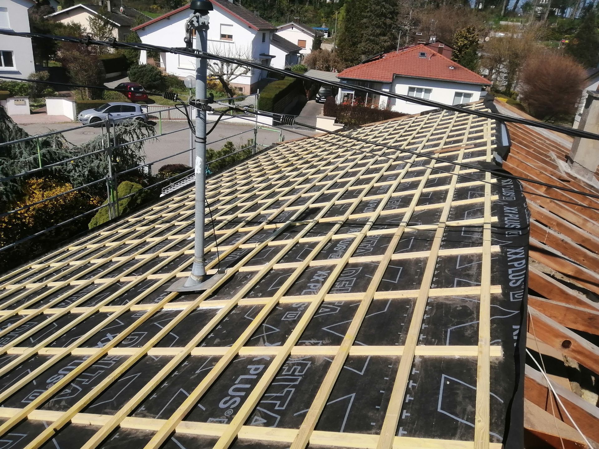 Toiture en construction avec charpente en treillis de bois et membrane d'étanchéité noire à proximité des maisons