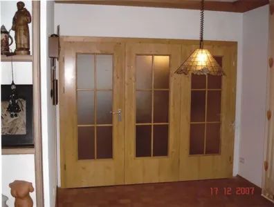 Eingangsbereich mit heller Holztür, Glaseinsätzen und Hängelampe aus Rattan