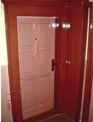 Rote Wand mit grauer Sockelleiste und braunem Bodenbelag in einem Innenraum.