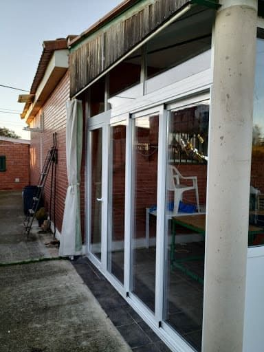Puertas corredizas de vidrio en un edificio de ladrillo con marcos blancos y un patio de concreto.