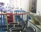 Mesas en el interior de un restaurante con sillas negras, barandillas azules y un camarero en un mostrador al fondo.