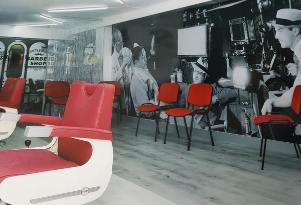 Salón moderno con sillas rojas, mesas blancas y obras de arte en blanco y negro en las paredes.