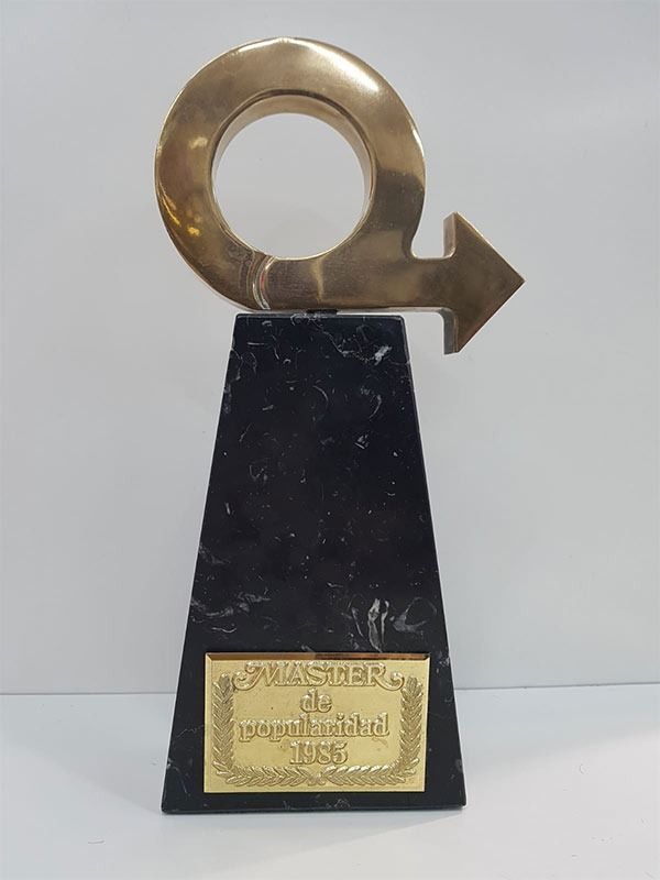 Trofeo de latón sobre una base negra con una placa dorada.