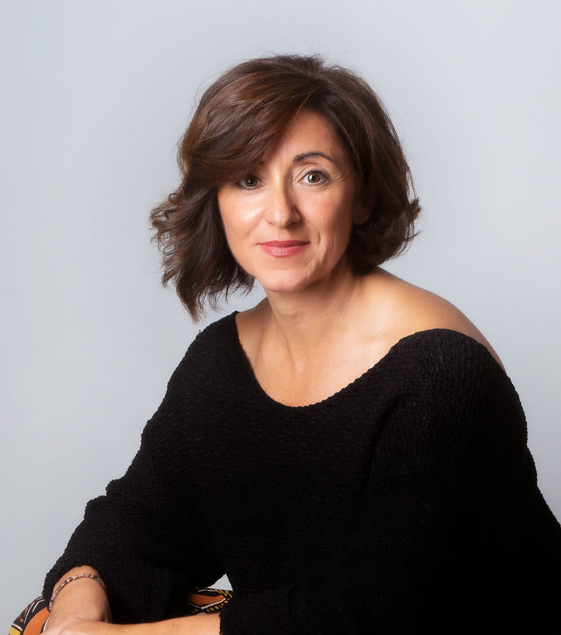 Mujer, María José Novillo Infantes, con Certificado de Excelencia 2024. Lleva labial rojo, viste de negro y está sobre un fondo blanco.