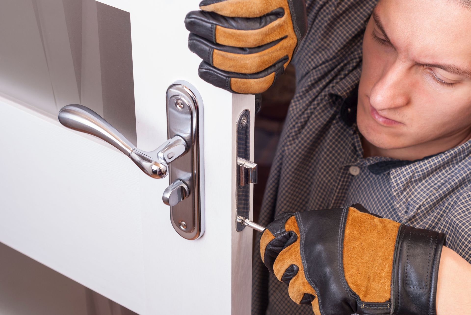 Une homme visse une nouvelle serrure sur une porte d'entrée