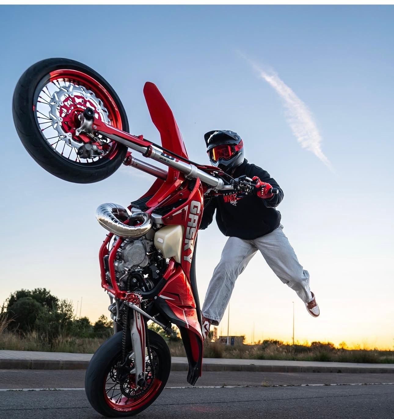 Un hombre está haciendo un truco en una motocicleta todoterreno naranja.