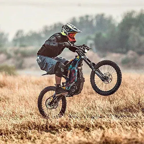 Un hombre está haciendo un truco en una motocicleta eléctrica en un campo.
