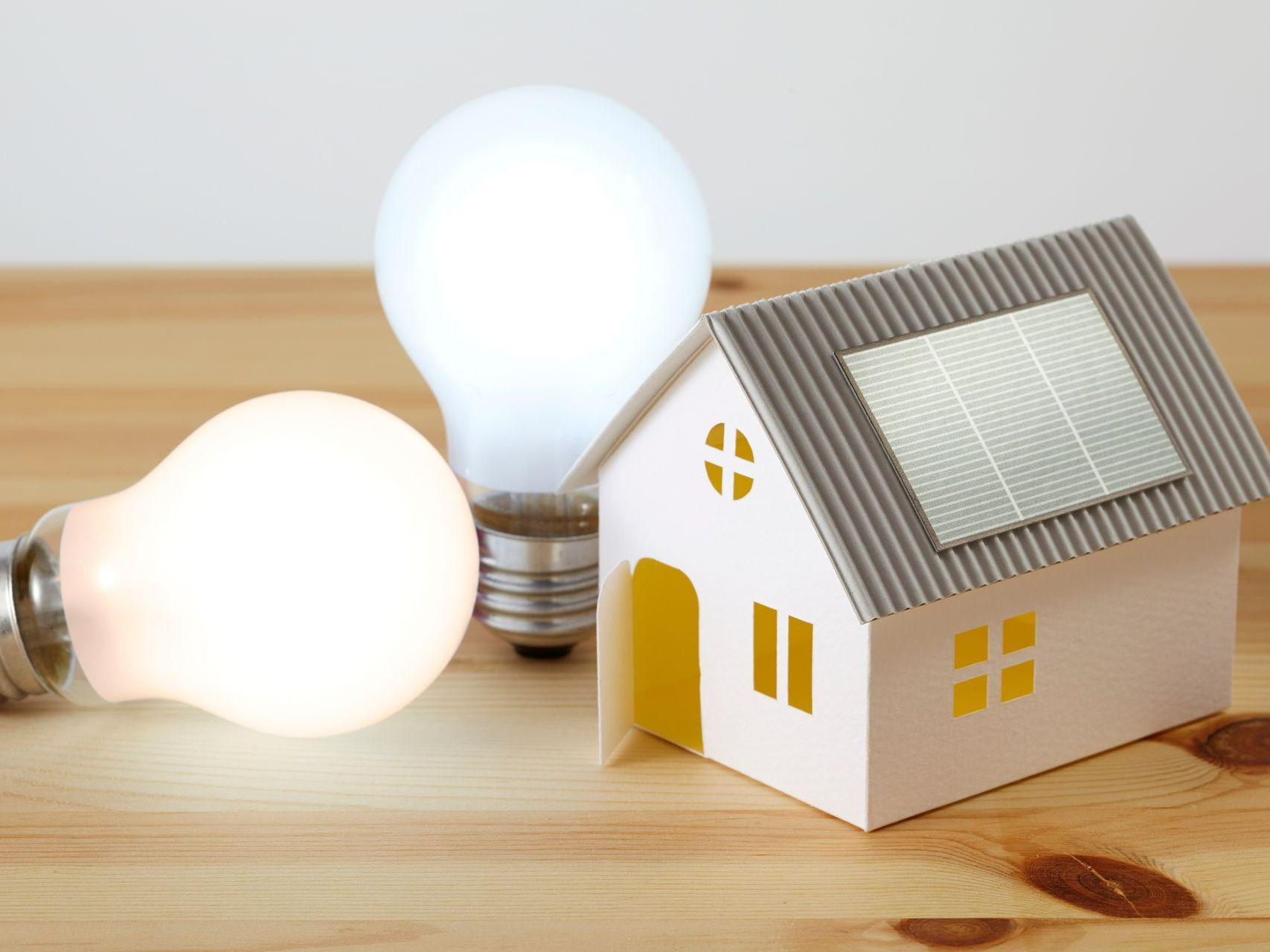 Deux ampoules avec une minimaison posés sur une table