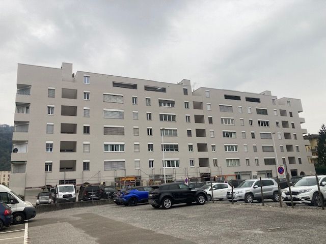 Un grande edificio con molte macchine parcheggiate davanti.