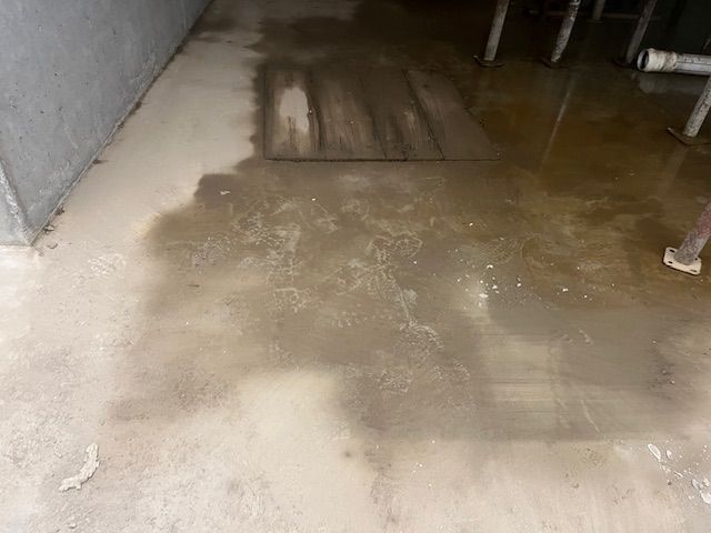 Un pavimento di cemento sporco con un foro di scarico al centro.