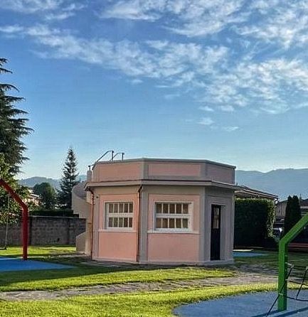 Una piccola casa rosa si trova in mezzo a un parco