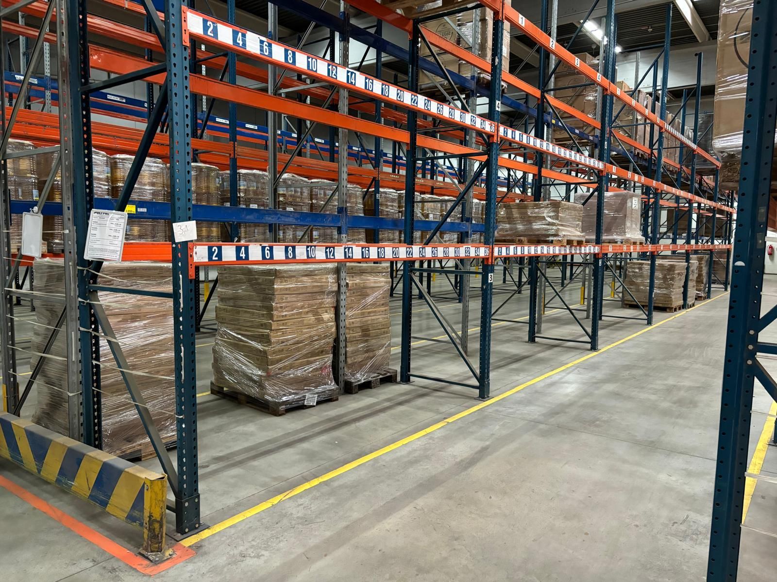 Mit Warenpaletten beladene Lagerregale, beleuchtet mit Deckenbeleuchtung. Farben: Blau, Orange und Hellbraun.