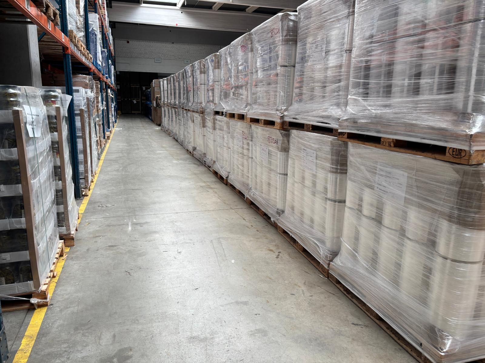 Lagergang mit Paletten verpackter Waren gesäumt.