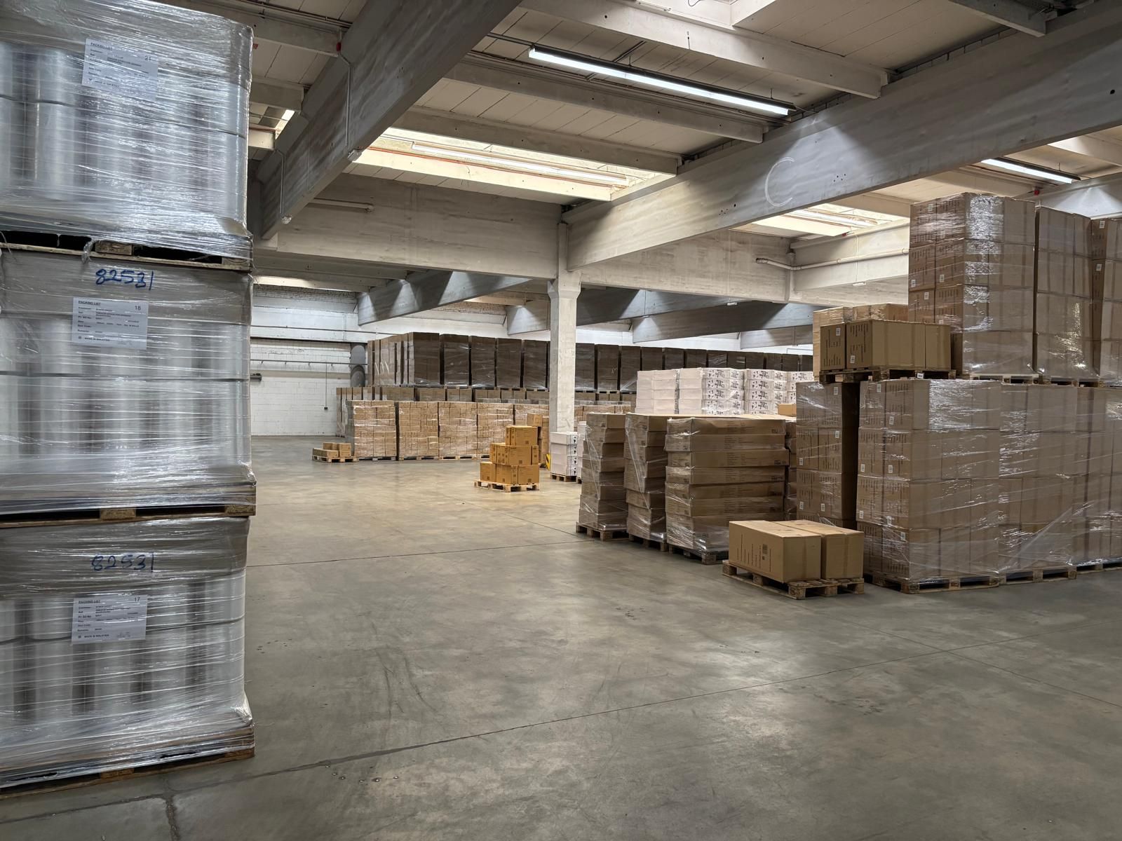 Lagerinnenraum mit Stapeln verpackter Kisten und Paletten.