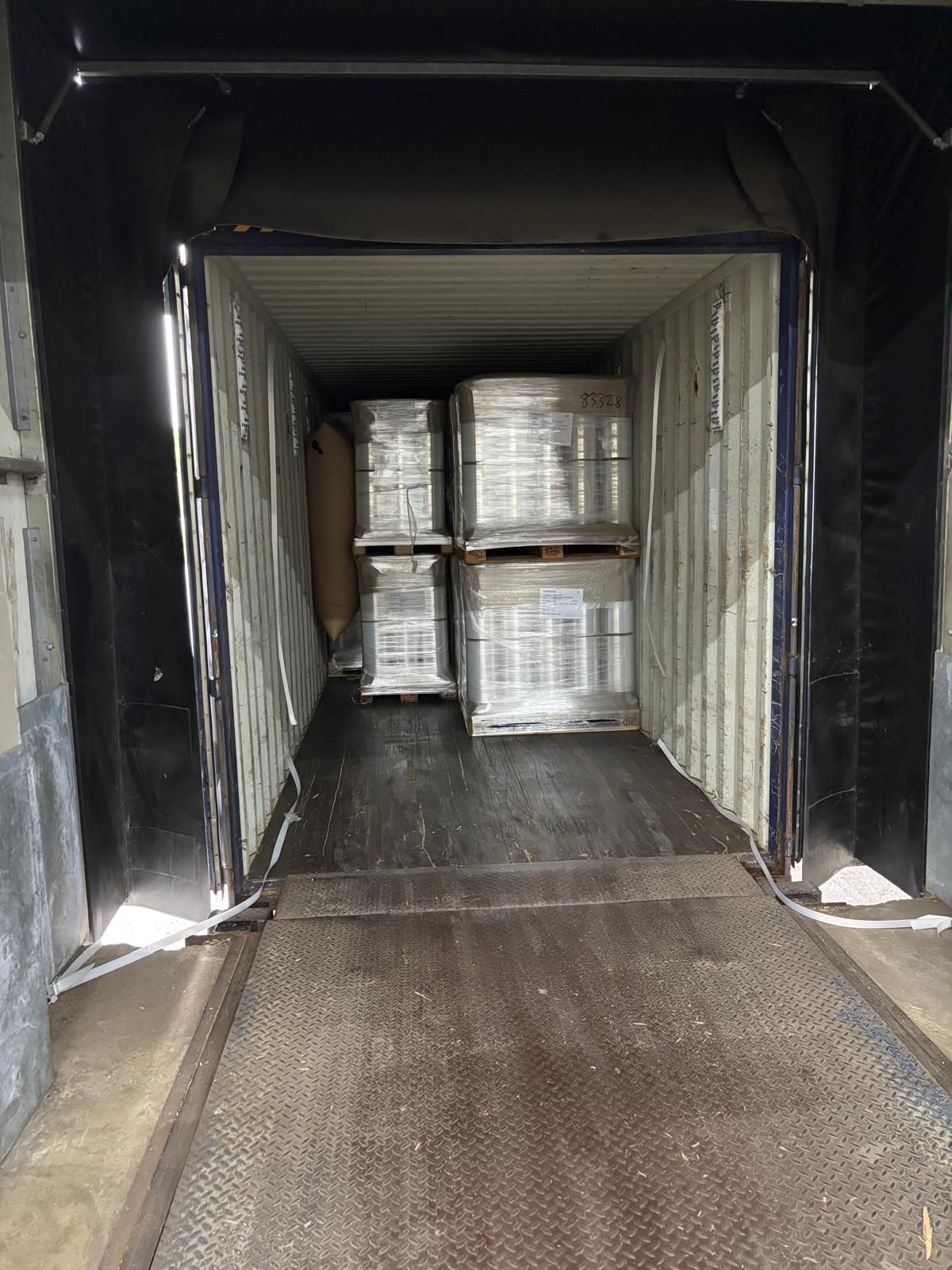 Ein mit mehreren Paletten verpackter Produkte beladener Container in einer Laderampe.