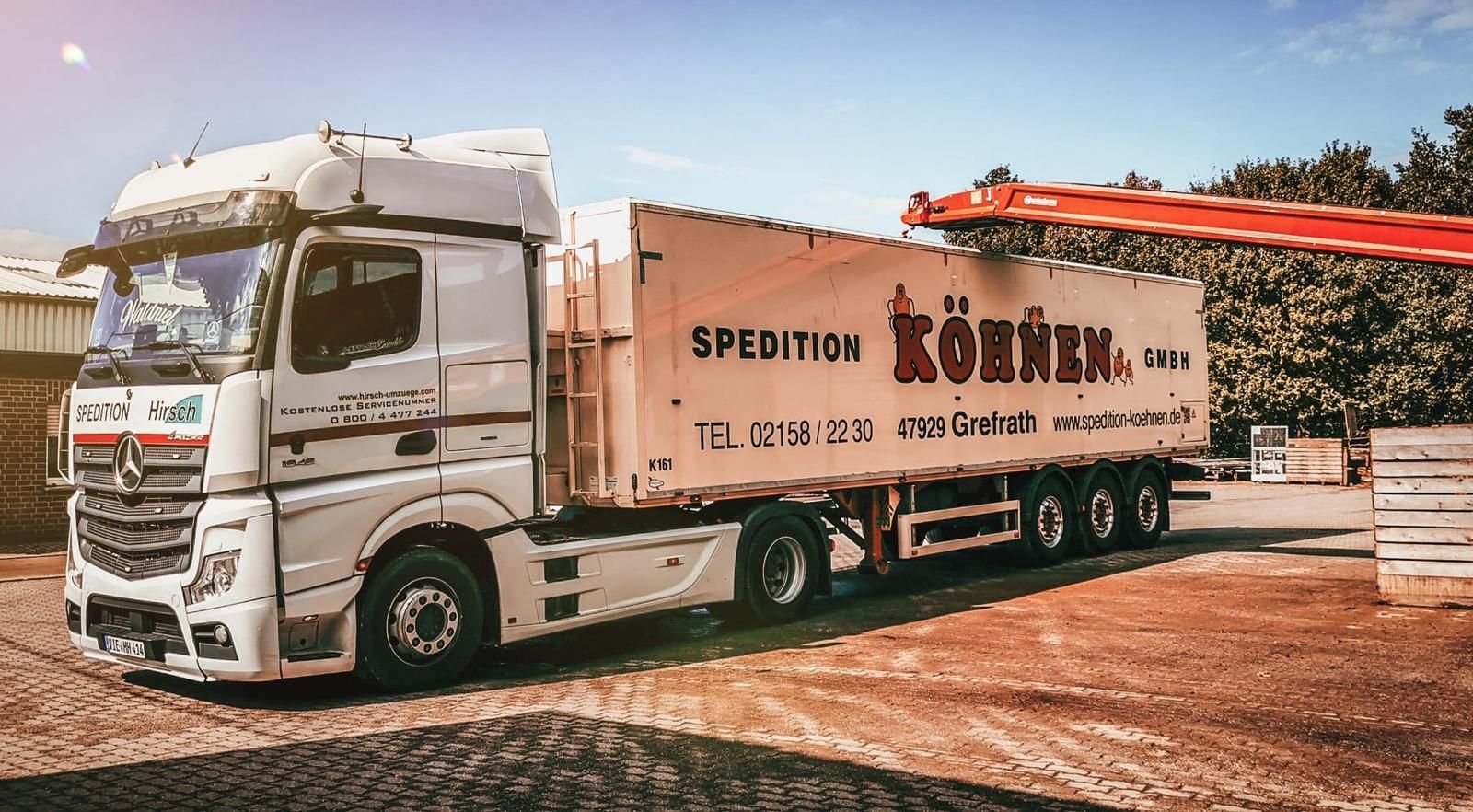 Weißer Sattelschlepper mit Anhänger, Aufschrift „Spedition Könen“, im Freien im Sonnenlicht geparkt.