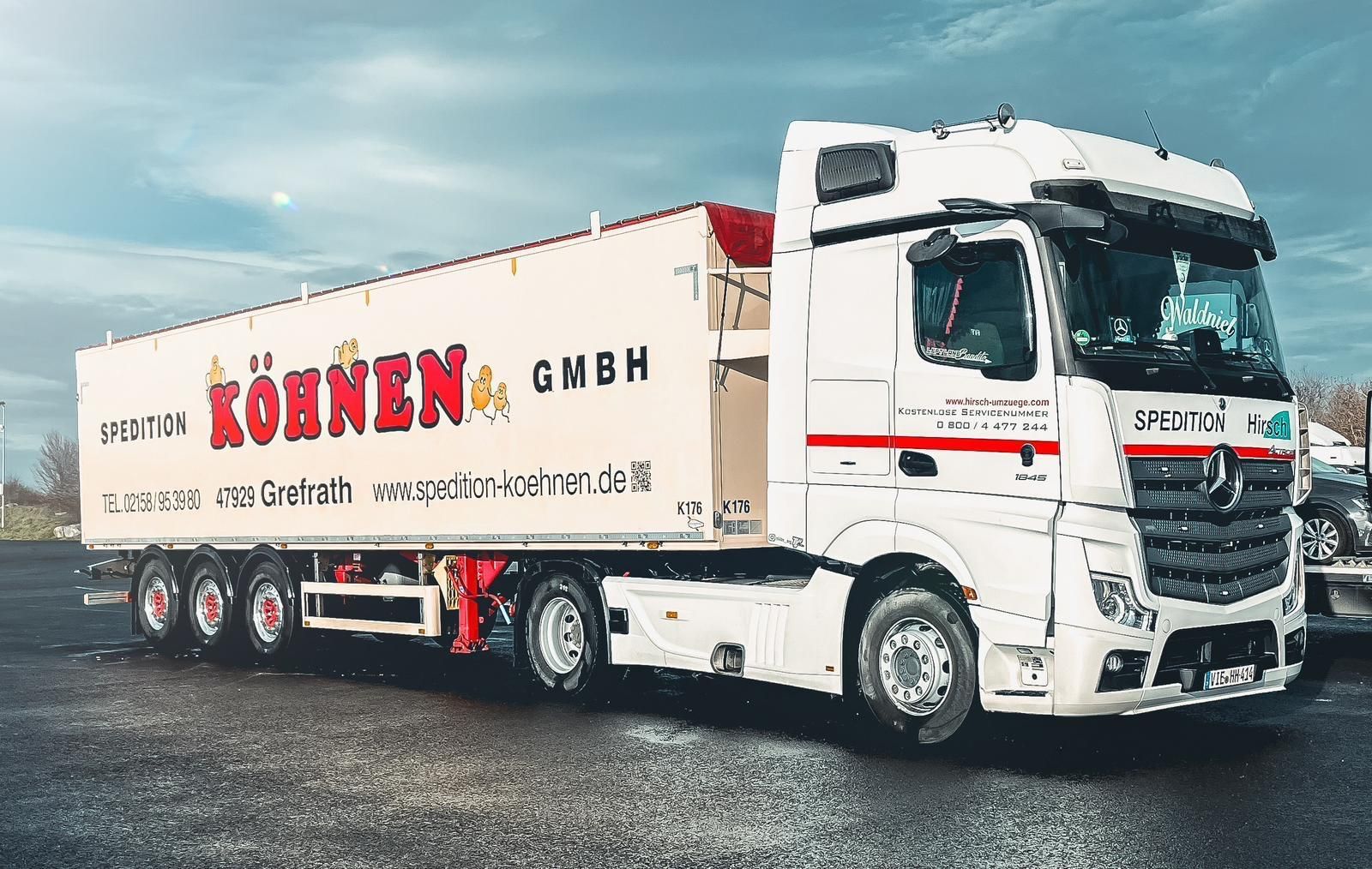 Weißer Sattelschlepper der Köhnen GmbH auf einem Parkplatz mit roten Akzenten an einem bewölkten Tag.