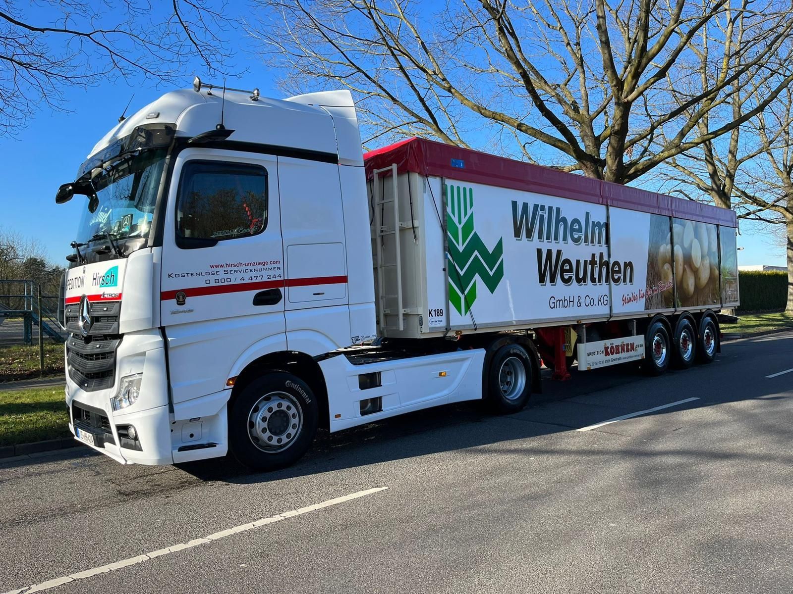 Weißer Sattelschlepper mit Anhänger „Wilhelm Weuthen“ am Straßenrand geparkt.