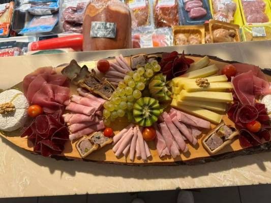 Une planche à découper en bois avec différents types de fromages et de raisins dessus