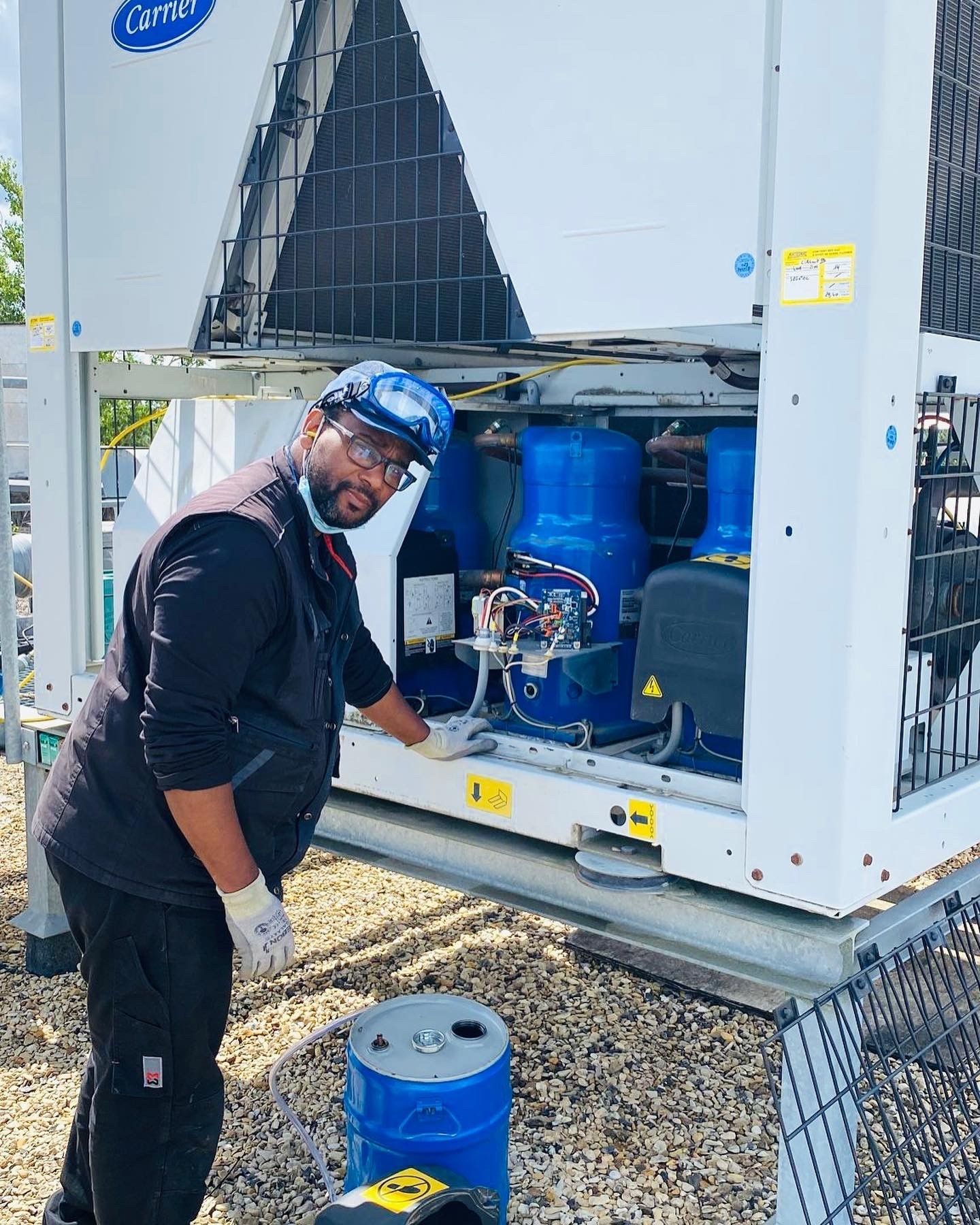 Un technicien travaille à l'extérieur sur un grand groupe frigorifique industriel Carrier.