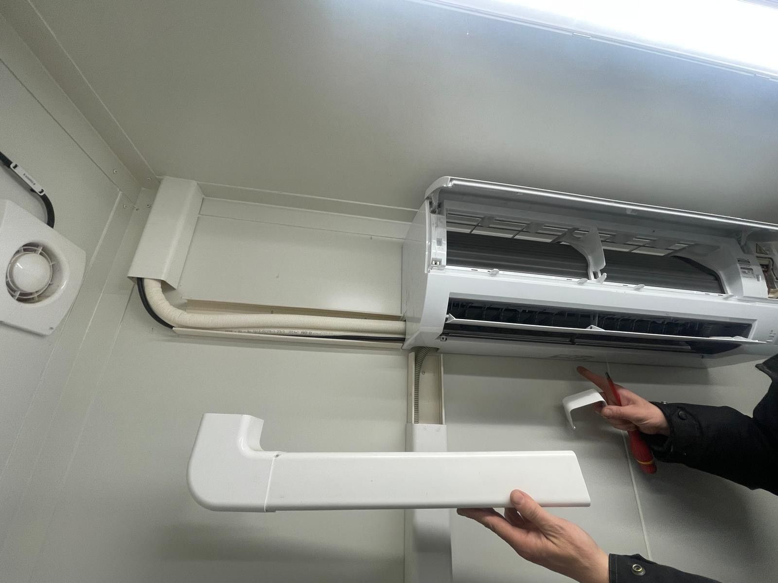 Une personne répare un climatiseur mural.