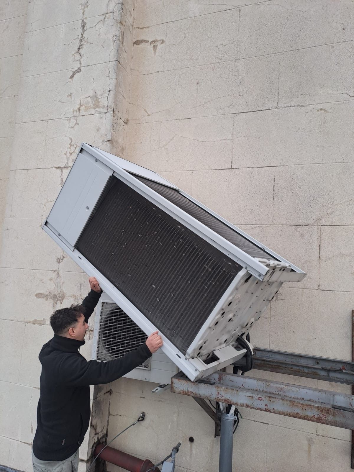 Une personne soutenant un grand climatiseur.