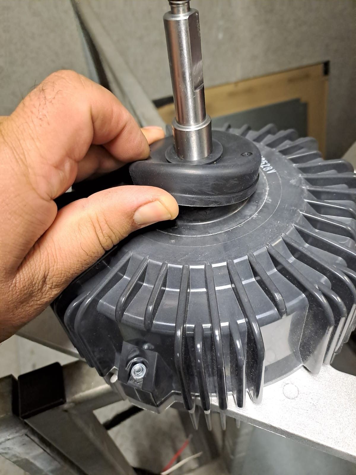 Une main maintient un joint en caoutchouc contre le centre d'un carter de moteur.