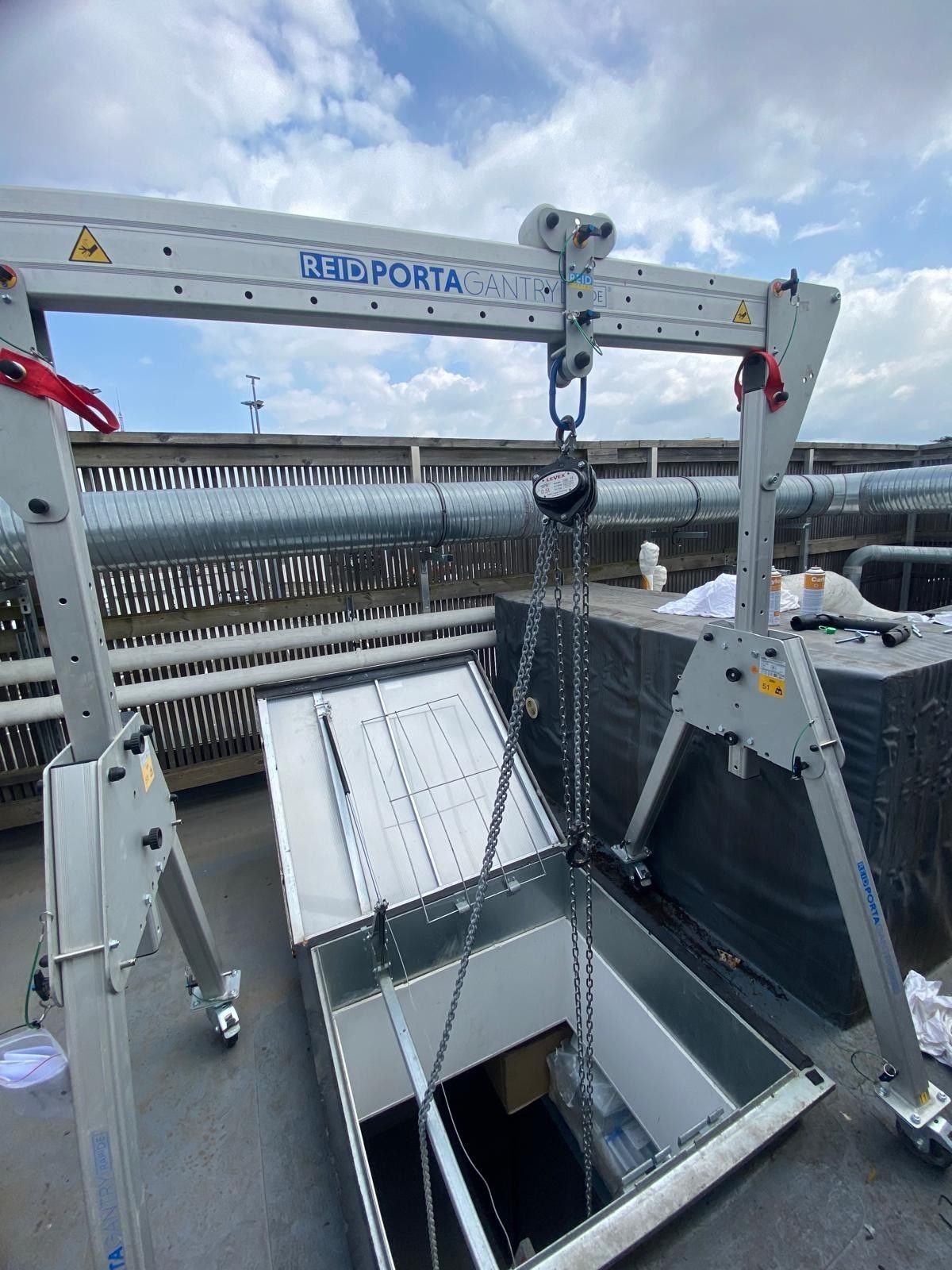 Une grue portique positionnée au-dessus d'une trappe de toit ouverte.