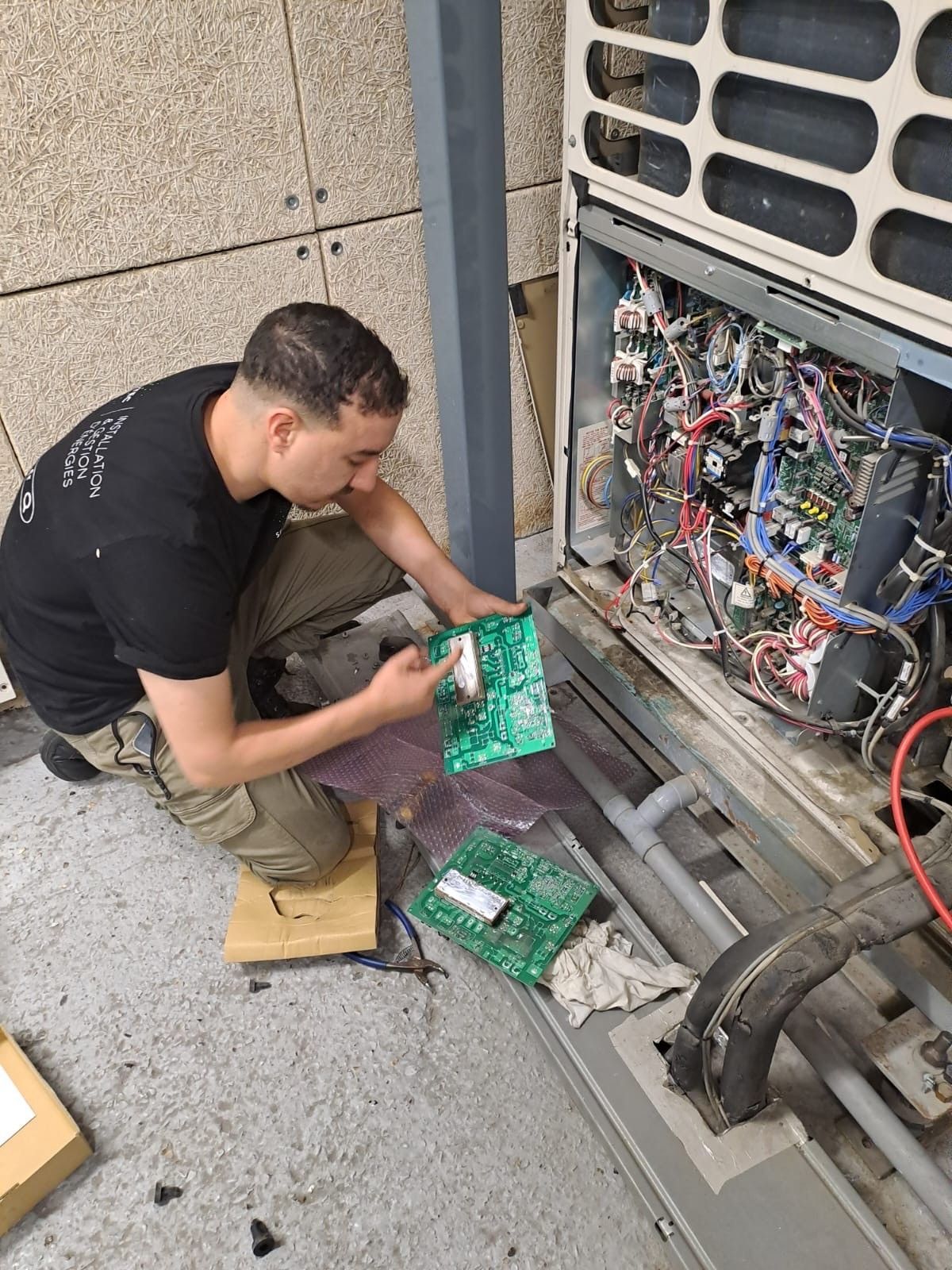 Un technicien répare une unité de climatisation extérieure.
