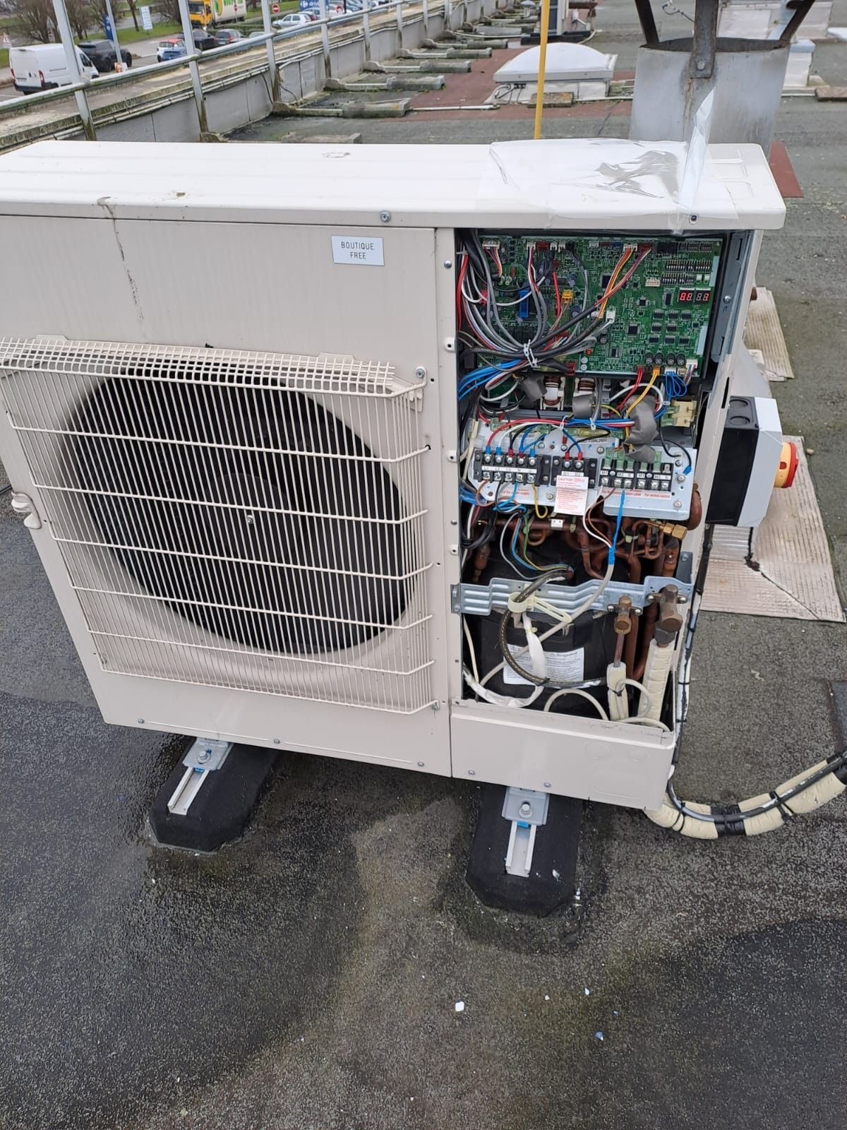 Unité de pompe à chaleur extérieure avec un panneau latéral ouvert laissant apparaître les composants électroniques.